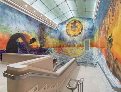 three painted walls, the left wall depicts a figure on bowing holding the a burning Grenfell tower, high up on the middle wall is Khadija Saye in circle holding an incense pot to her ear, on the third wall shows mythical beings playing instruments