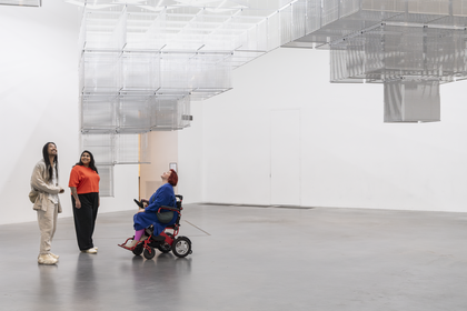 Three gallery visitors looking up at an artwork on the ceiling